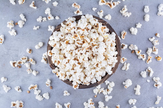 Popcorn in una ciotola e sparsi dappertutto sulla superficie di marmo