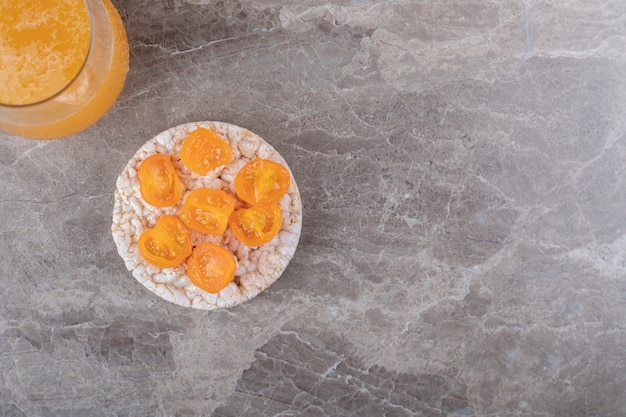 Porridge con fette di pomodoro in un bicchiere su una spremuta di arancia, sulla superficie di marmo