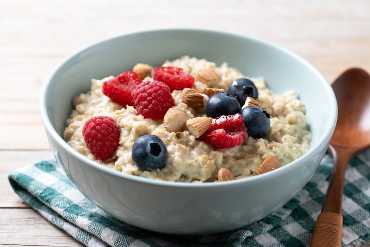 Foto gratuito porridge di farina d'avena con lamponi mirtilli e mandorle in una ciotola su un tavolo di legno