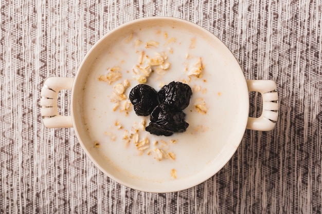 Porridge di farina d&#39;avena con prugne secche nere nella ciotola