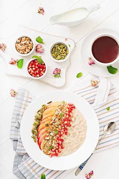 Porridge di farina d'avena gustoso e sano con mele, melograno e noci. Colazione salutare. Cibo fitness. Nutrizione appropriata. Vista dall'alto.