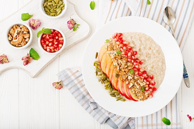 Porridge di farina d'avena gustoso e sano con mele, melograno e noci. Colazione salutare. Cibo fitness. Nutrizione appropriata. Vista dall'alto.