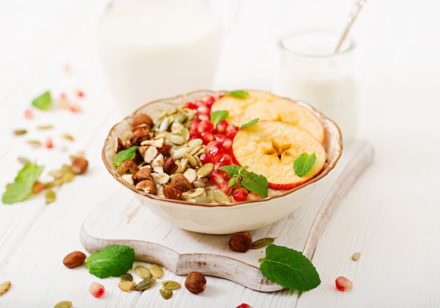 Porridge di farina d'avena gustoso e sano con mele, melograno e noci. Colazione salutare. Cibo fitness. Nutrizione appropriata