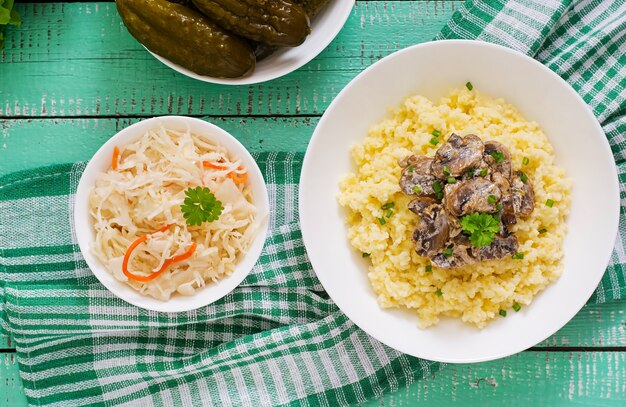 Porridge di miglio con funghi in una ciotola bianca.