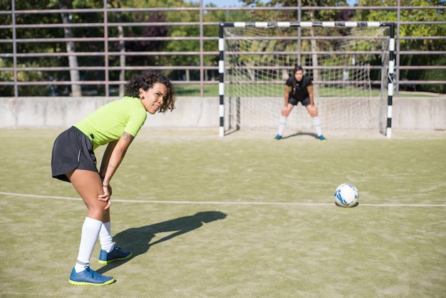 Portiere femminile concentrato in piedi negli obiettivi. Sportiva in uniforme scura che si prepara a prendere la palla. Sport, tempo libero, stile di vita attivo