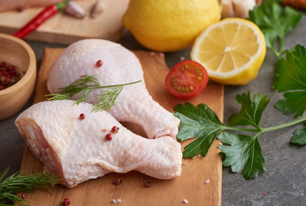 porzioni fresche di carne di pollo per cucinare e grigliare con condimento fresco. Coscia di pollo cruda cruda sul tagliere.