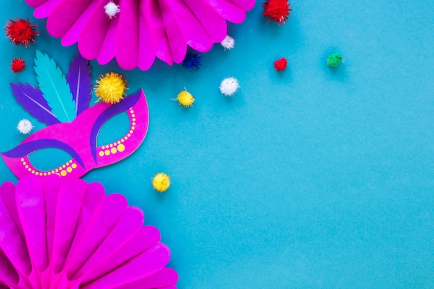 Posa piatta di maschera di carnevale e ventagli di carta con pompon