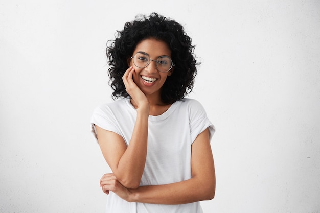 Positiva amichevole giovane donna di razza mista con capelli ricci bruna sorridente allegramente