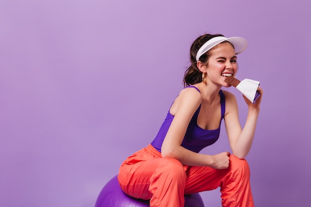 Positiva la donna dai capelli scuri in protezione morde la barretta di cioccolato