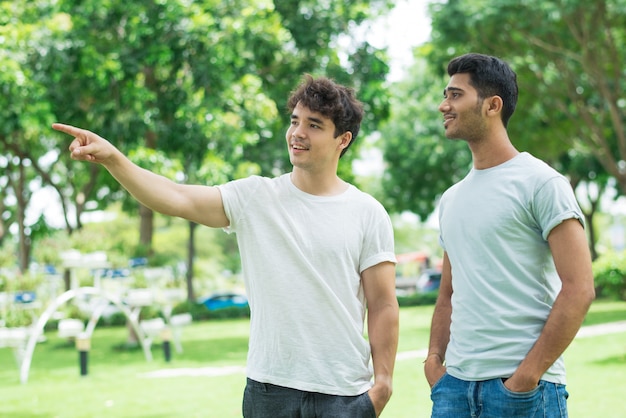 Positivo ragazzo amichevole che mostra la direzione per l&#39;uomo indiano