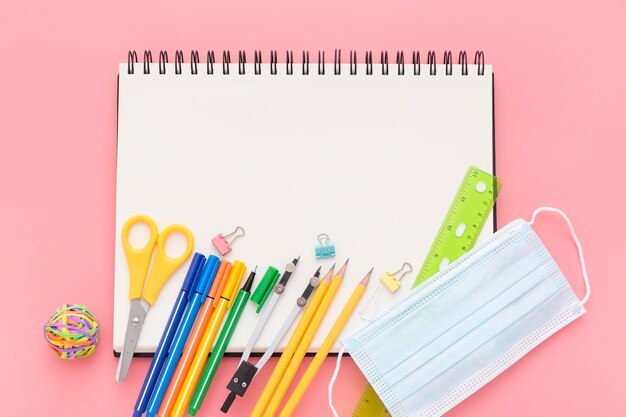 Posizionamento piatto di rifornimenti scolastici con quaderno e matite