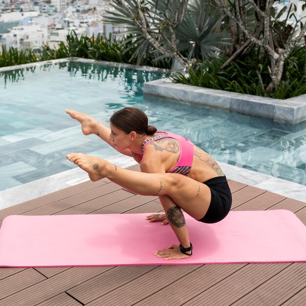Posizione di yoga di pratica della donna in piscina all'aperto
