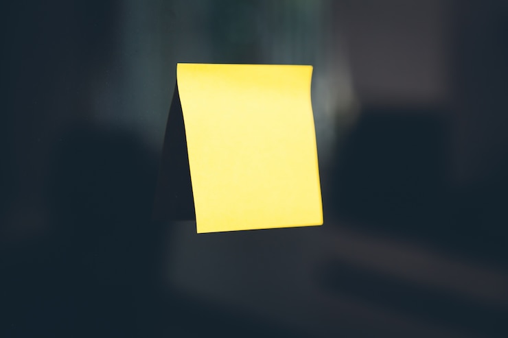 Foto gratuito post-it giallo bloccato su una parete nera