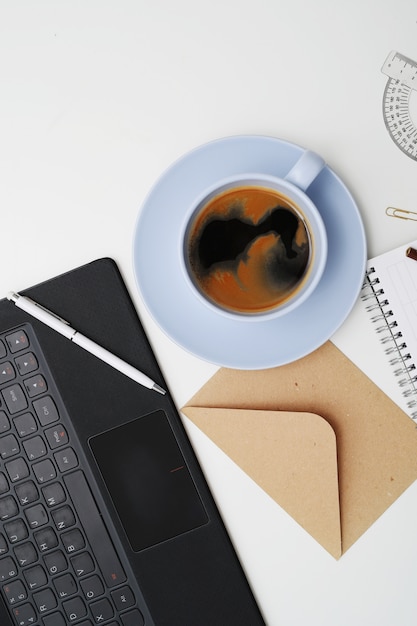 Posto di lavoro con laptop, caffè e blocco note, vista dall'alto