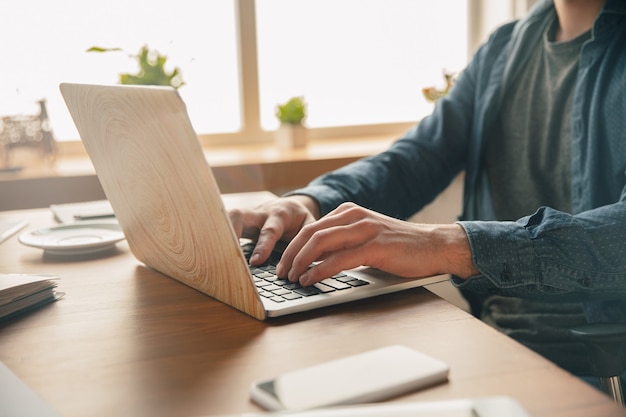 Posto di lavoro creativo: spazio di lavoro organizzato come preferisci per l'ispirazione. Uomo che lavora in ufficio in abbigliamento comodo, posizione rilassata e tavolo disordinato. Scegli l'atmosfera che desideri - ideale chiaro o caos.