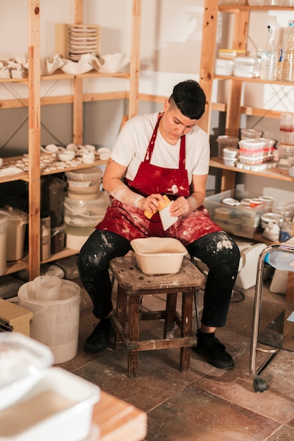 Potter femminile che pulisce le piccole mattonelle con la spugna nell&#39;officina