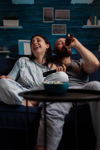 POV di un uomo e una donna allegri che ridono di un film comico sul canale TV, divertendosi a casa. Coppia felice guardando film divertenti in un programma televisivo, facendo attività ricreative per l'intrattenimento.