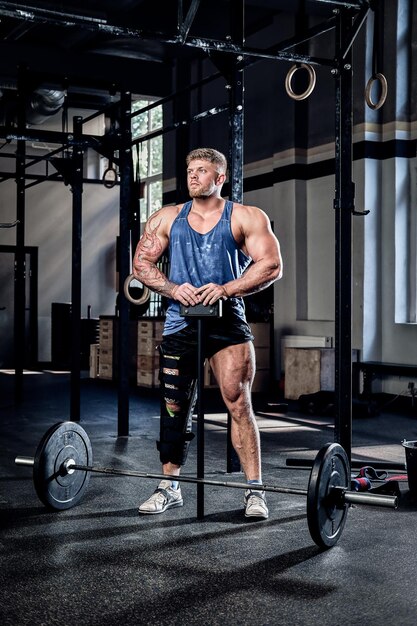 Powerlifter professionista con una benda su una gamba, con in mano un martello sportivo, riscaldamento prima dell'allenamento, recupero dagli infortuni. Sport, impegno, motivazione