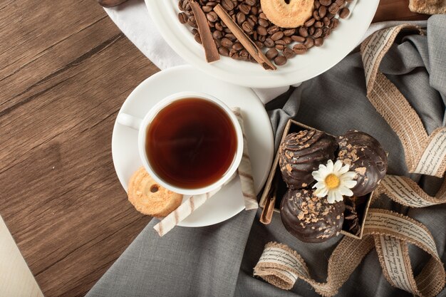 Praline e biscotti al cioccolato in un piattino con una tazza di tè