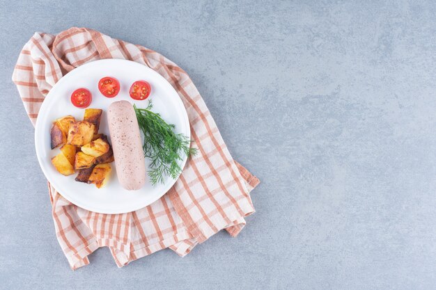 Pranzo perfetto. Patate fritte e salsiccia bollita sulla zolla bianca