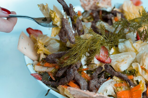 Prendendo cibo da insalata di carne di verdure con una forchetta