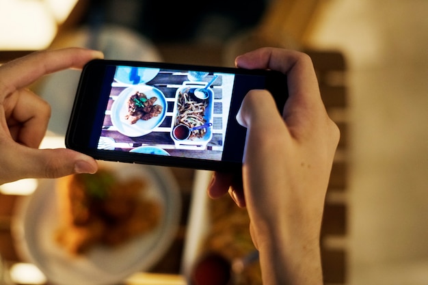Prendendo la foto di smartphone di un concetto di media sociali piatto cena