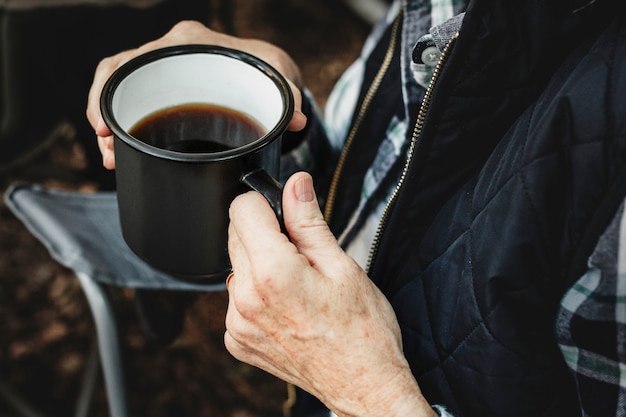 Prendendo un caffè vicino alla tenda nella foresta