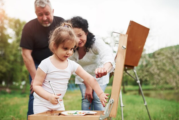 Prendi un altro colore per questo. Nonna e nonno si divertono all'aperto con la nipote. Concezione della pittura