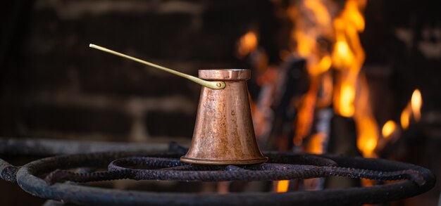 Prepara il caffè in un turco su un fuoco aperto. Il concetto di un'atmosfera accogliente e bevande.