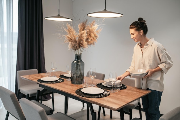 Prepararsi per la cena. Giovane donna dai capelli scuri che serve il tavolo in cucina