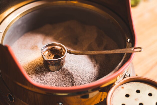 Preparazione del caffè turco nel cezve sulla sabbia al bar caffetteria