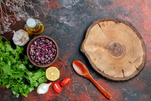 Preparazione della cena con cibi e una bottiglia di olio di fagioli vassoio di legno e un mazzo di verde sulla tavola di colori misti