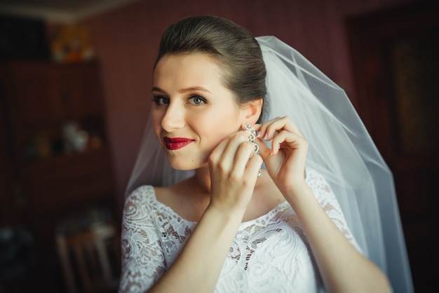 Preparazione nuziale per la cerimonia nuziale. sposa mettendo su gioielli