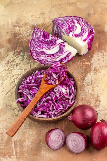 Preparazione vista dall'alto per una sana insalata con cavolo rosso e cipolle su uno sfondo di legno con spazio per le copie