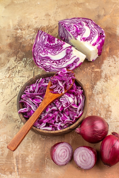 Preparazione vista dall'alto per una sana insalata con cavolo rosso e cipolle su uno sfondo di legno con spazio per le copie