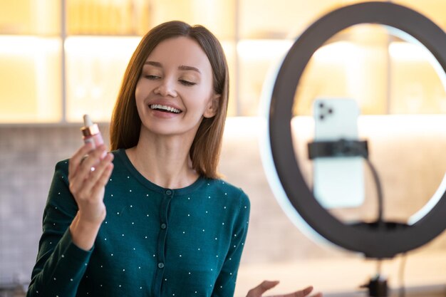 Presentazione in linea. Giovane donna che rappresenta la nuova crema per il viso e sembra coinvolta