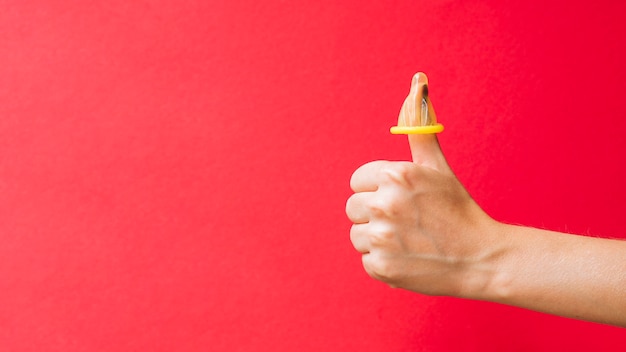 Preservativo giallo del primo piano sul dito della donna