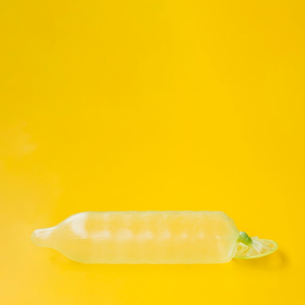 Preservativo riempito con acqua su sfondo giallo