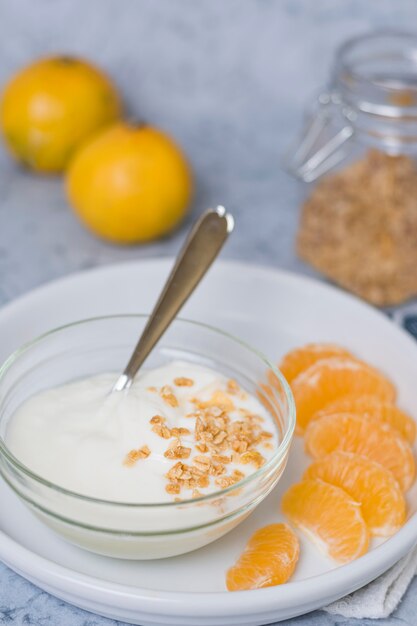 Prima colazione sana del primo piano con yogurt e l'arancia