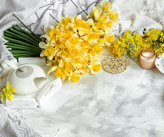 Primavera ancora in vita con una tazza di tè e fiori. Sfondo chiaro, casa fiorita e accogliente.