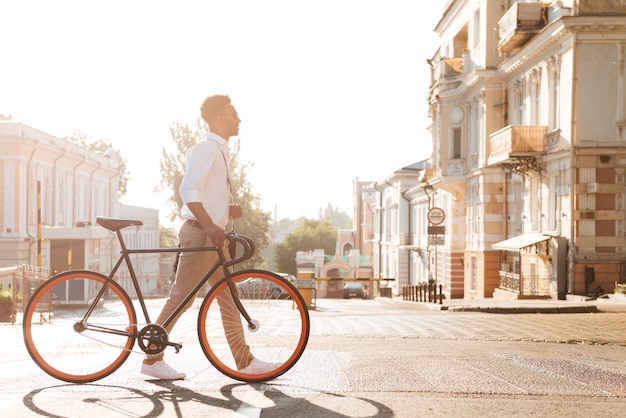 Primo mattino africano dell'uomo con la bicicletta che cammina all'aperto