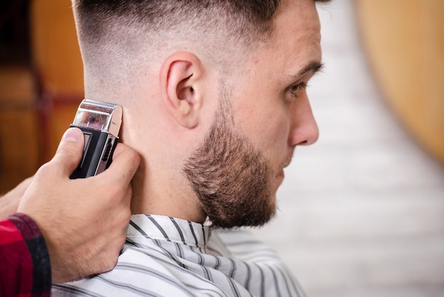 Primo piano barbiere finendo un taglio di capelli