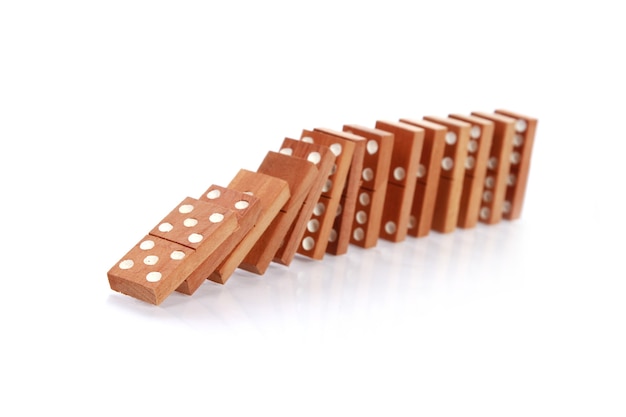 Primo piano dei domino di legno che cadono su una superficie bianca