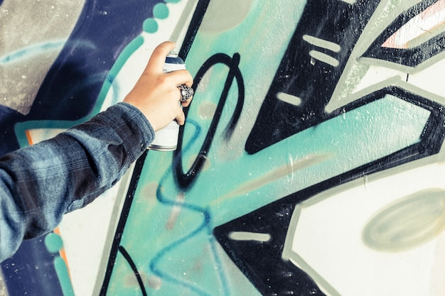 Primo piano dei graffiti della pittura della mano di un artista sulla parete