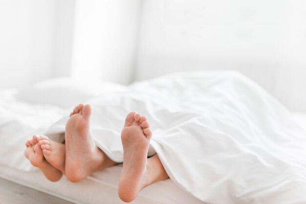 Primo piano dei piedi di due fratelli sul letto