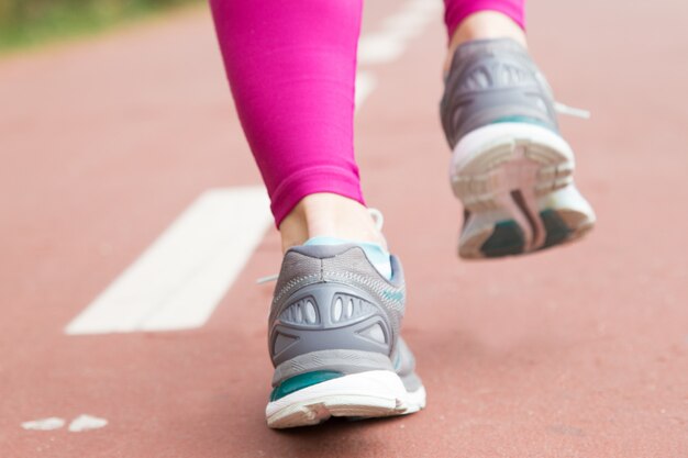 Primo piano dei piedi femminili in scarpe sportive sullo stadio