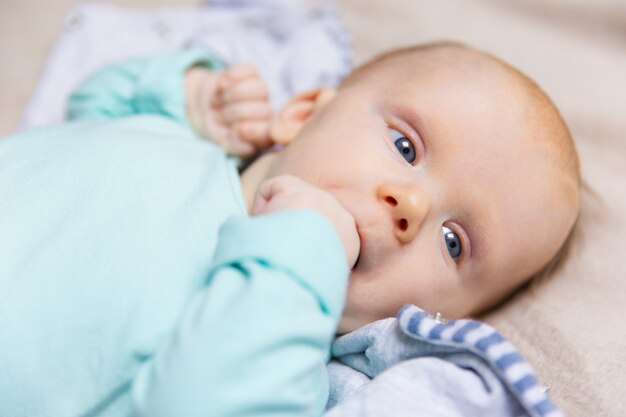 Primo piano del bambino dolce pensieroso con il dito in bocca