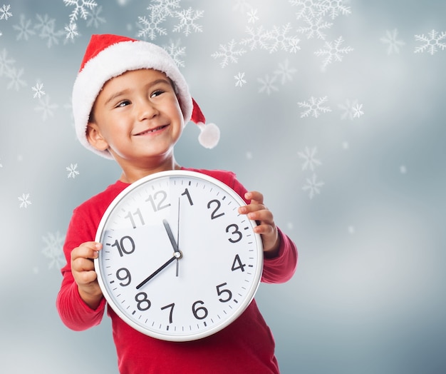 Primo piano del bambino eccitato con un orologio su sfondo Natale