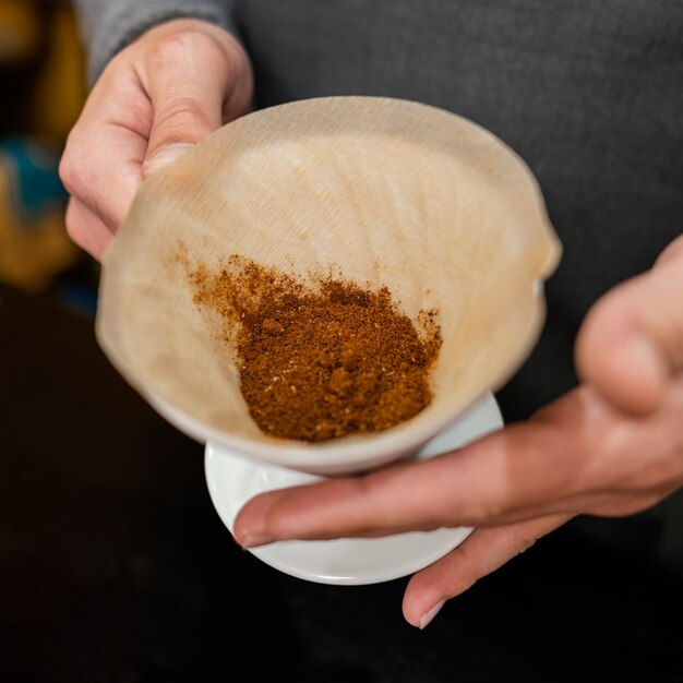 Primo piano del barista maschio che tiene filtro con caffè