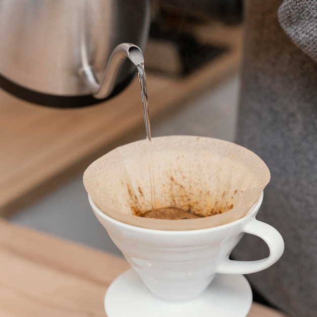 Primo piano del barista maschio versando acqua calda sul filtro del caffè